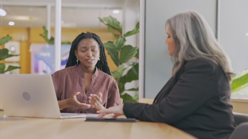 Two women sitting at desk with laptop